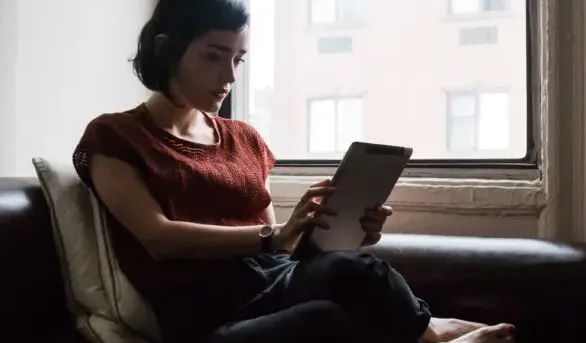 Nexi - Frau auf Couch mit Tablet in den Händen